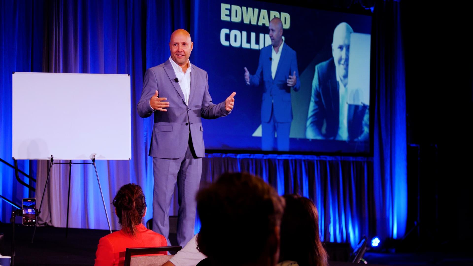 Edward Collins speaking with attendees at a business conference.